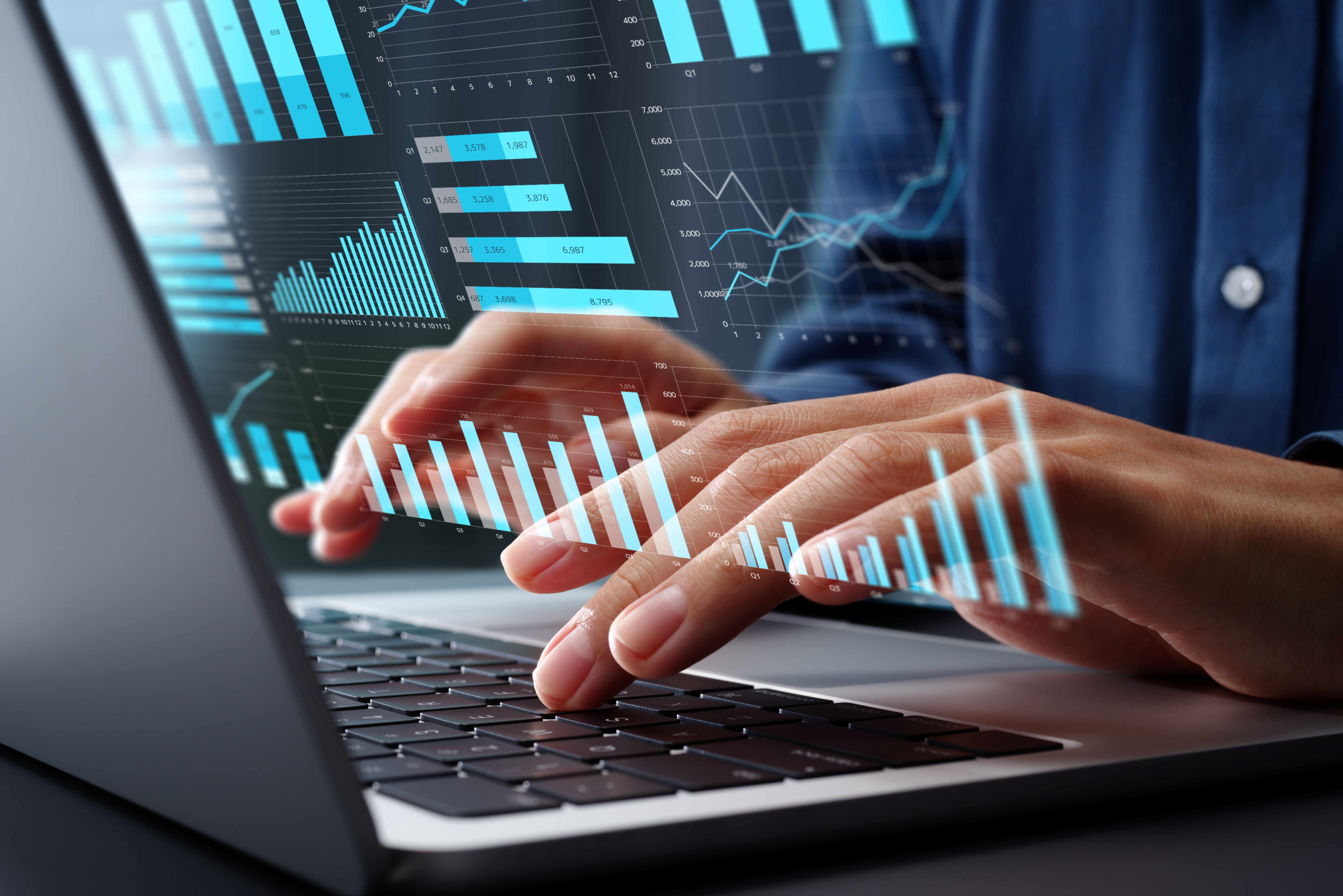 Zwei Hände tippen auf der Tastatur eines Laptops, während grafische Darstellungen von Datenanalysen, wie Balken- und Liniendiagramme, über den Bildschirm projiziert werden.